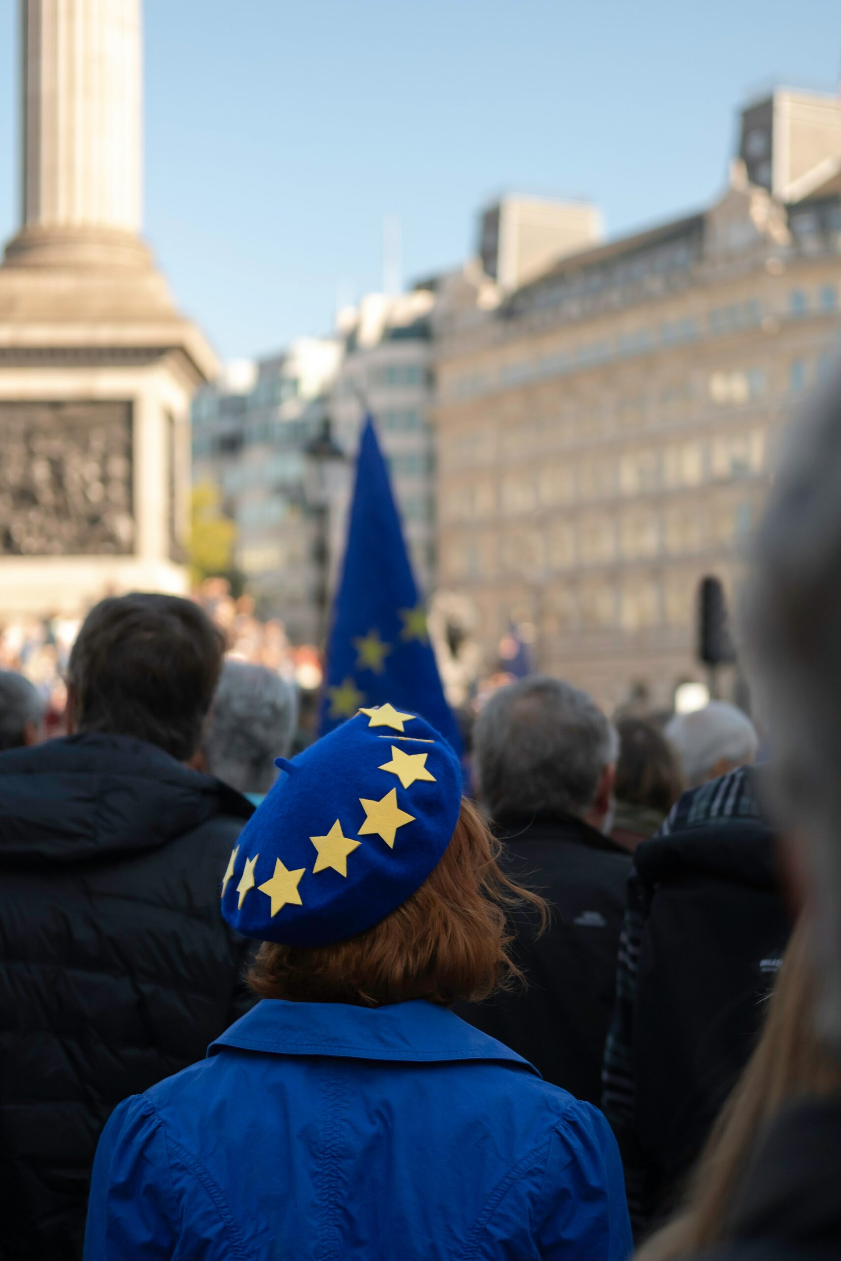 A girl pictured fromthe back wearing a hat with european colors and stars