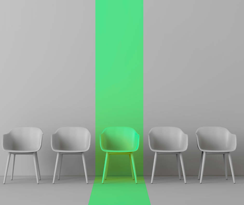 Numerose sedie grigie tranne una verde al centro che simula l'assunzione